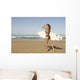 Young woman with surfboard on beach Wall Mural