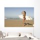 Young woman with surfboard on beach Wall Mural