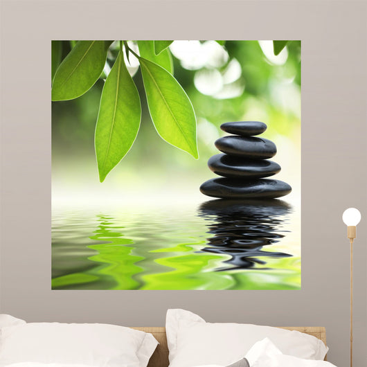 Zen stones pyramid on water surface, green leaves over it Wall Mural