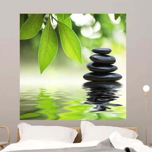 Zen stones pyramid on water surface, green leaves over it Wall Mural