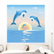 Jumping dolphins in front of a sunset over sea Wall Mural