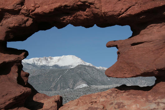Pikes Peak mountain as seen through a hole in red rocks at Garde Wall Mural
