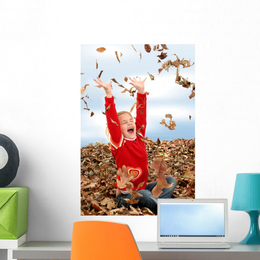 happy seven year old girl playing in pile of leave Wall Mural