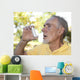 Elderly man using asthma inhaler outdoors Wall Mural