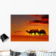 Desert landscape with walking camels at sunset Wall Mural
