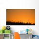 A Grassy Field With The Sun Setting Behind It Wall Mural