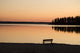 A Bench Silhouetted At Sunset Near The Lake Wall Mural