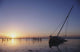 Partly Submerged And Keeling Sail Boat In Silhouette At Sunset Wall Mural