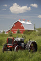 Old Red Tractor In A Field With A Red Barn In The Background Wall Mural