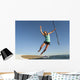A Woman Jumps Into The Water Off A Surf Board While Holding Her Paddle Wall Mural