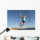 A Woman Jumps Into The Water Off A Surf Board While Holding Her Paddle Wall Mural