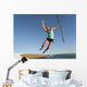 A Woman Jumps Into The Water Off A Surf Board While Holding Her Paddle Wall Mural