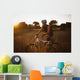 A Man Riding His Bike Through Tall Grass At Sunset Wall Mural