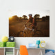 A Man Riding His Bike Through Tall Grass At Sunset Wall Mural