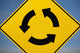 A Yellow Sign Showing Three Arrows Going In A Circle Wall Mural