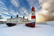 Boats Sitting On A Frozen Surface With A Lighthouse And Building Wall Mural