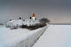 A Snow Covered Fence With A Lighthouse And Building In The Background Wall Mural