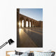 A row of archways against a blue sky and sunlight shining through Wall Mural