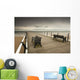 A Wooden Pier With Benches Looking Out Over The Beach And Water Wall Mural