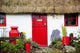 Traditional Irish Cottage With A Red Door And Red Decorative Items Wall Mural