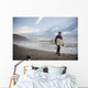 A Young Man Carries His Surfboard Down The Beach Wall Mural