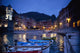 Boats Moored By Buildings Along The Waterfront At Night Wall Mural