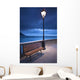 A Bench And Light Post Along The Railing On The Coast Wall Mural