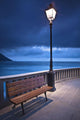 A Bench And Light Post Along The Railing On The Coast Wall Mural
