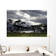 Sunlight Shining Through The Dark Clouds With Trees On The Shoreline Wall Mural