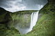 A Waterfall Over A Grassy Cliff Wall Mural