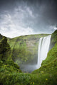 A Waterfall Over A Grassy Cliff Wall Mural