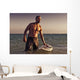 A Man With His Surfboard In The Water At Sunset Wall Mural