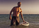 A Man With His Surfboard In The Water At Sunset Wall Mural