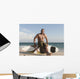 A Man Sits On His Surfboard On The Beach Wall Mural