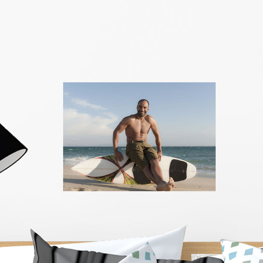 A Man Sits On His Surfboard On The Beach Wall Mural