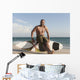 A Man Sits On His Surfboard On The Beach Wall Mural