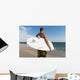 A Man Standing On The Beach Holding His Surfboard Wall Mural