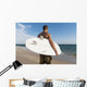 A Man Standing On The Beach Holding His Surfboard Wall Mural
