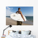 A Man Standing On The Beach Holding His Surfboard Wall Mural