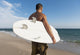 A Man Standing On The Beach Holding His Surfboard Wall Mural
