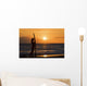 Female Surfer On Beach Silhouetted Against Orange Sunset Over Ocean Wall Mural