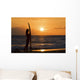 Female Surfer On Beach Silhouetted Against Orange Sunset Over Ocean Wall Mural