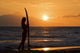 Female Surfer On Beach Silhouetted Against Orange Sunset Over Ocean Wall Mural