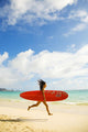 Young Japanese Woman Running On Beach While Holding A Red Surfboard Wall Mural