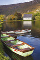 St Finbarre's Oratory And Rowing Boats On Shore Of Gougane Barra Lake Wall Mural
