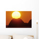 Sun Setting In Orange Sky Over Ocean And Silhouetted Hill Wall Mural