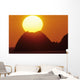 Sun Setting In Orange Sky Over Ocean And Silhouetted Hill Wall Mural