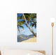 Hammock tied between palm trees on sandy beach Wall Mural