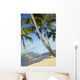 Hammock tied between palm trees on sandy beach Wall Mural