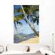 Hammock tied between palm trees on sandy beach Wall Mural